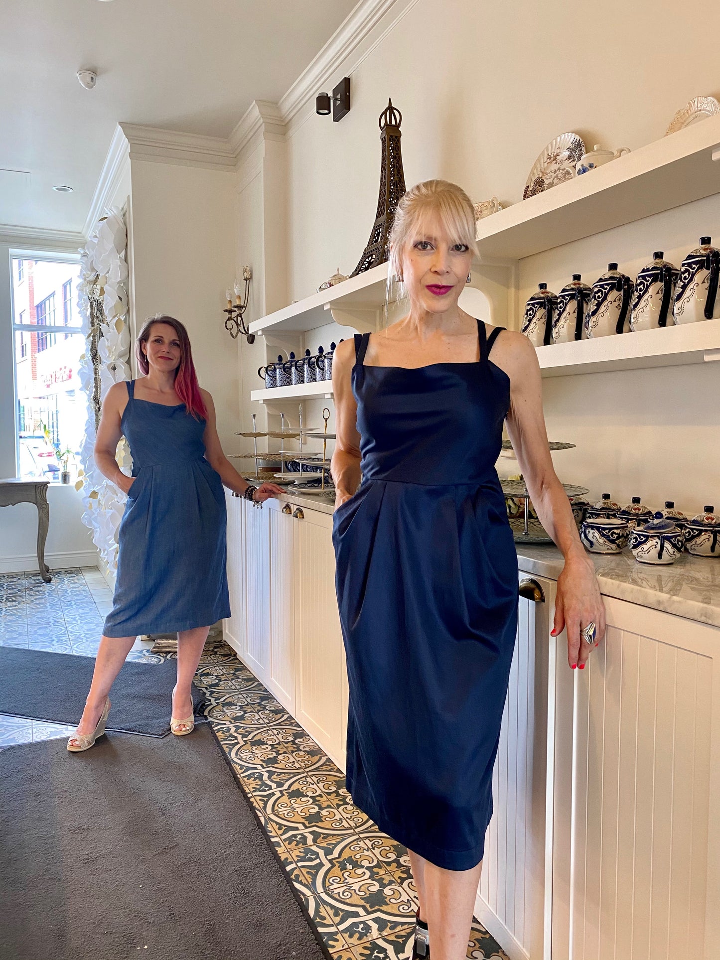 Two models stand leaning against the counter at Cafe Crystal in Barrhaven. One wears denim Tencel and the other midnight stretch sateen Tencel Lindon dresses